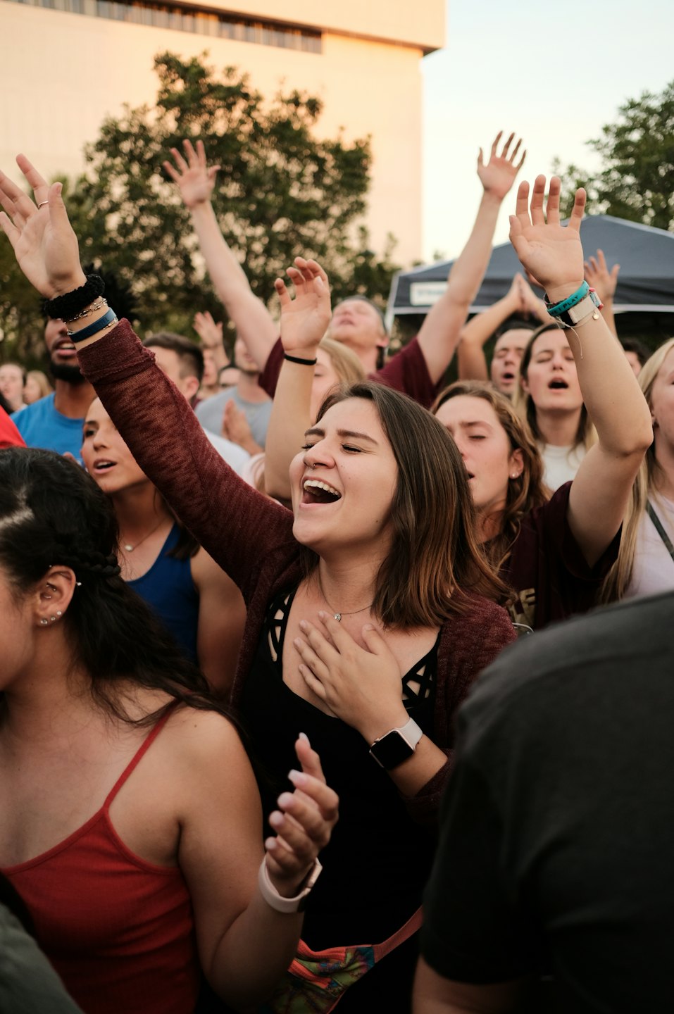 Un grupo de personas cantando y celebrando en un evento al aire libre.