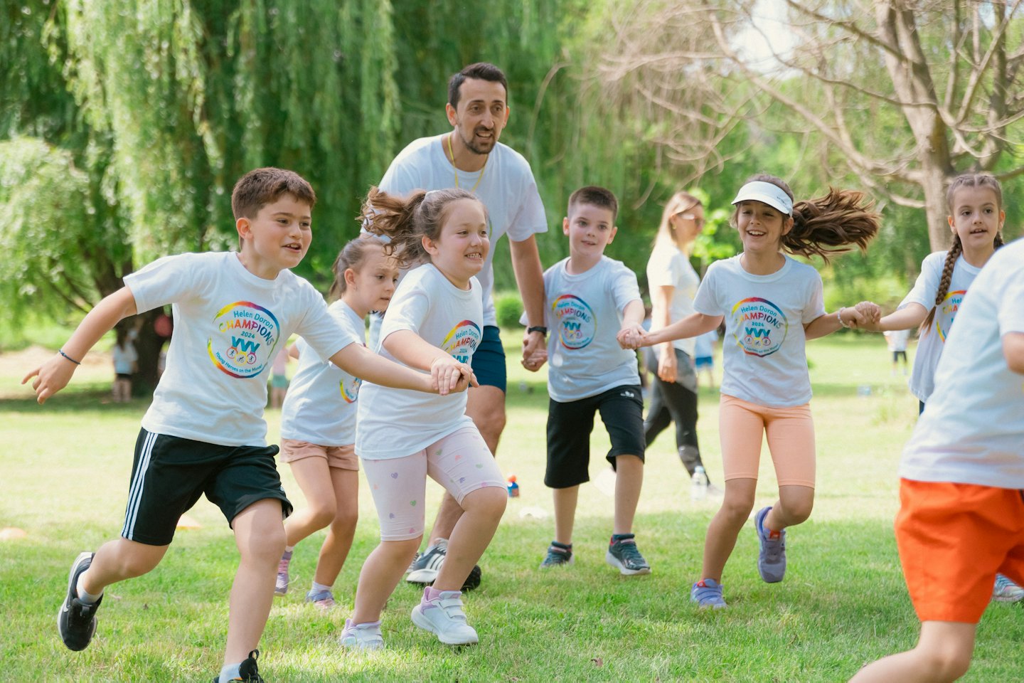 Un hombre y niños con camisetas de marca juegan en un parque.